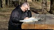 Man reading a book outdoors on a bench