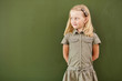 Scoolgirl standing near blackboard