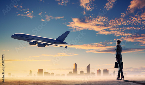 Photo: Business woman looking at airplane in sky Business woman looking at airplane in sky