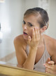 Foto: Concerned young woman in bathroom checking skin condition Concerned young woman in bathroom checking skin condition