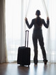 Silhouette of business woman with wheel bag looking into window