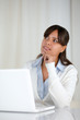 Pensive young woman working on laptop computer