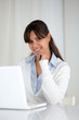 Smiling young woman looking at you using laptop