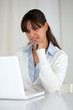 Pensive young woman reading on laptop screen