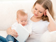 Mother reading a book a little baby on the sofa
