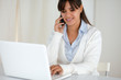 Smiling woman working and speaking on cellphone
