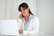 Smiling young woman looking at you using laptop