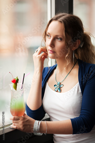 Photo: Sad woman with coctail looking out the window Sad woman with coctail looking out the window