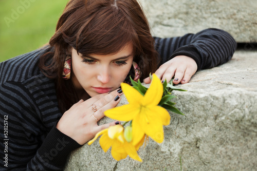Photo: Young woman with a flowers lying on the tombstone Young woman with a flowers lying on the tombstone
