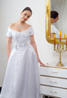 Beautiful bride in wedding dress standing beside mirror