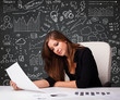 Photo: Businesswoman sitting at desk with business scheme and icons Businesswoman sitting at desk with business scheme and icons