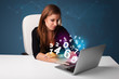 Photo: Beautiful young woman sitting at desk and typing on laptop with Beautiful young woman sitting at desk and typing on laptop with