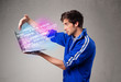 Photo: Casual man holding laptop with exploding data and numbers Casual man holding laptop with exploding data and numbers