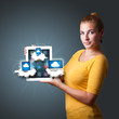 Photo: young woman holding tablet with modern devices in clouds young woman holding tablet with modern devices in clouds