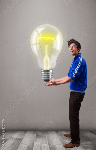 Photo: Attractive man holding realistic 3d light bulb Attractive man holding realistic 3d light bulb