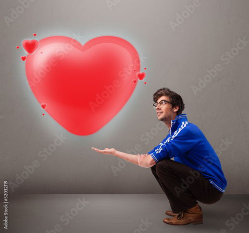 Photo: Young man holding lovely 3d red heart Young man holding lovely 3d red heart