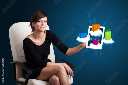 Photo: woman holding modern tablet with colorful shopping bags on cloud woman holding modern tablet with colorful shopping bags on cloud