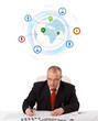 businessman sitting at desk with a globe and social icons