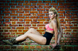 girl with pink bra posing  in front of a brick wall