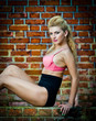 girl in swimsuit posing provocatively in front of a brick wall