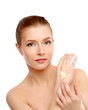 Young woman putting cream on her face
