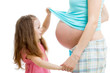 kid girl looking at pregnant mother's belly