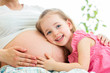 happy kid girl hugging pregnant mother's belly