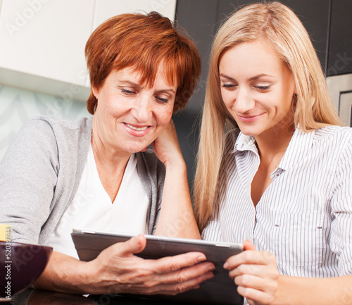 Photo: Mother and daughter looking in tablet pc Mother and daughter looking in tablet pc