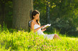 A young woman lying on the grass and reading a book