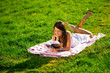 A young woman lying on the grass and reading a book