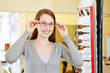 Young woman with new glasses at optician