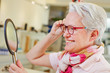 Foto: Elderly woman with glasses looking in mirror Elderly woman with glasses looking in mirror