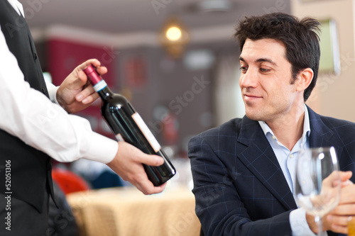 Photo: Waiter suggesting a bottle of wine to a customer Waiter suggesting a bottle of wine to a customer