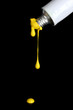 Yellow paint follows from the tube on black background close-up