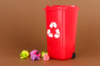 Recycling bin with papers on brown background