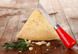 Piece of Parmesan cheese with knife on wooden table close-up