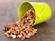 Overturned bucket with nuts on wooden background