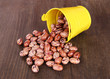 Overturned bucket with beans on wooden background