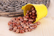 Overturned bucket with beans on wooden background