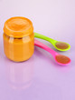 Baby food with weaning spoons on purple background