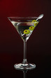 Martini glass with olives on dark red background