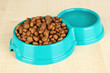 Dry dog food in bowl on wooden background