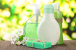 Cosmetics bottles and natural handmade soap on green background