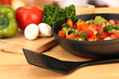 Vegetable ragout in pan,  on wooden table on bright background