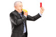 A mature businessman blowing a whistle and showing a red card