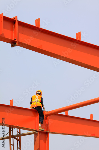 Photo: a worker working on red steel beam a worker working on red steel beam