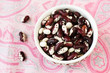 One bowl with red and white beans on pink tablecloth