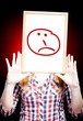 Woman showing sad emoticon in front of face