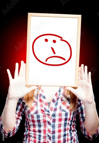 Photo: Woman showing sad emoticon in front of face Woman showing sad emoticon in front of face