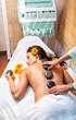 Photo: Stone therapy. Woman getting a hot stone massage in spa salon Stone therapy. Woman getting a hot stone massage in spa salon